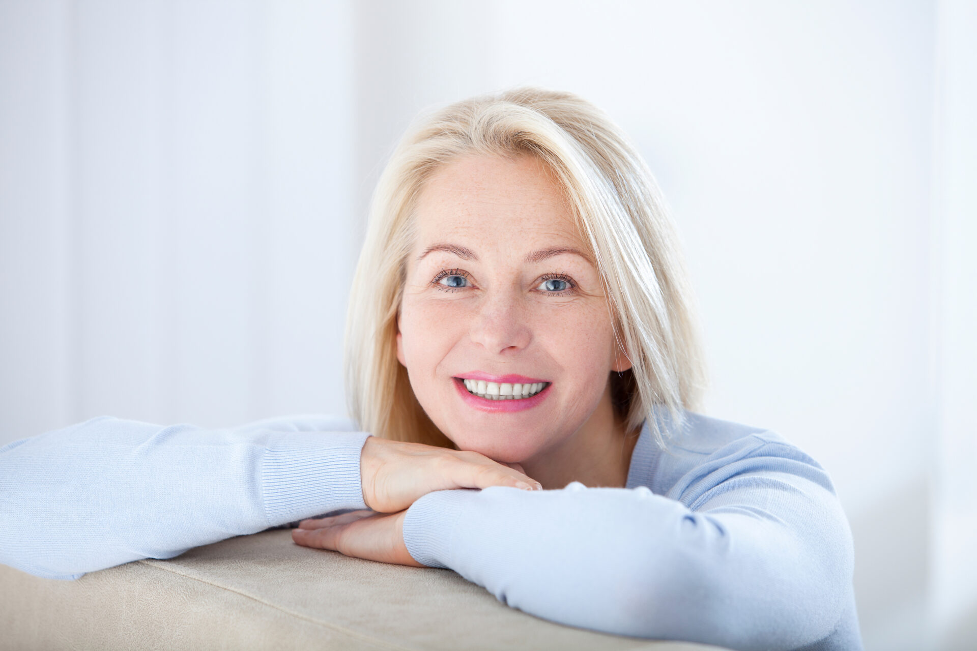 Active beautiful middle-aged woman smiling friendly and looking in camera. Woman’s face closeup. Realistic images without retouching with their own imperfections. Selective focus.