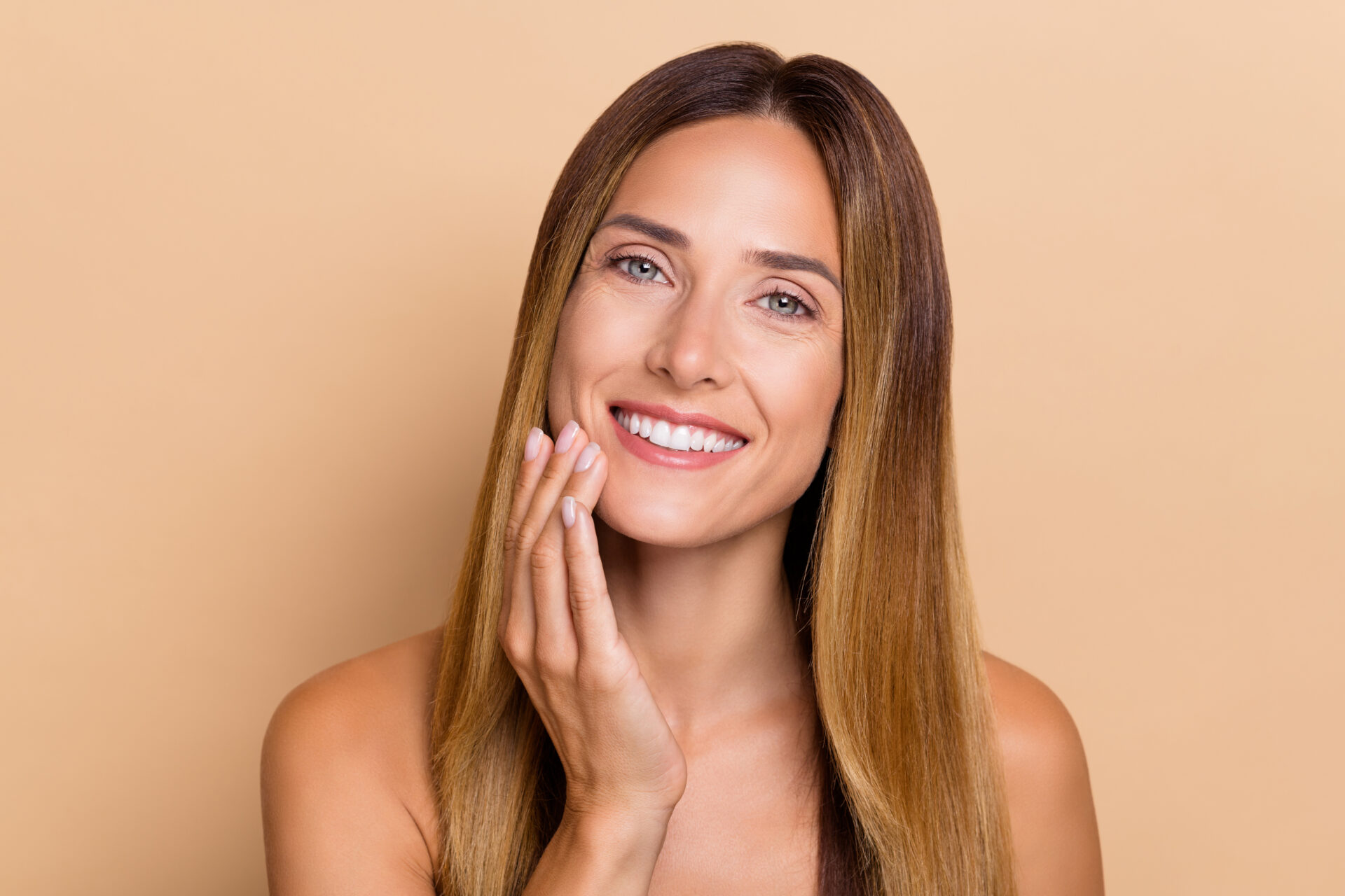 Portrait of attractive cheery long-haired woman touching soft flawless skin lifting uplift isolated over beige pastel color background