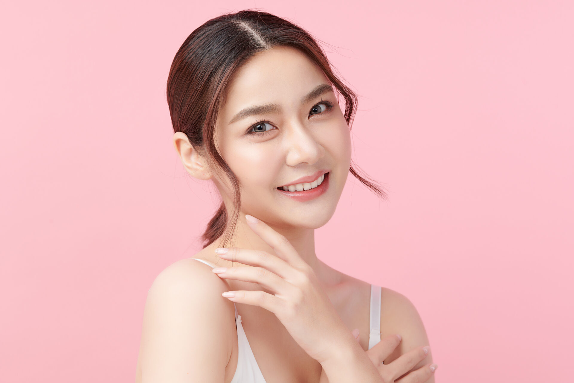 Beautiful young asian woman with clean fresh skin on pink backgr